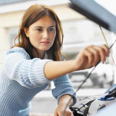 SIGNS THAT YOUR CAR NEEDS A MECHANIC image of woman with long brown hair raising the hood of her car to check out noise