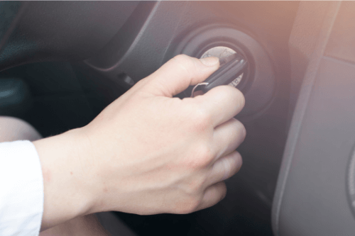 A woman's hand starting a car, need ignition repair service.