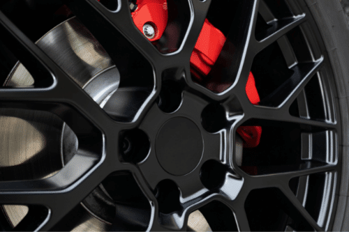 Wait! Is It Necessary to Replace Brake Calipers in Klein, TX? with Repair One Auto. Closeup image of a red brake caliper shown through a black rim of car tire