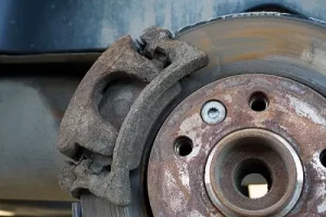 What Happens If You Don't Replace Your Brake Pads? | Repair One in Klein/Sprin, TX. Closeup image of worn-out brake pad, disc rotor, and caliper.
