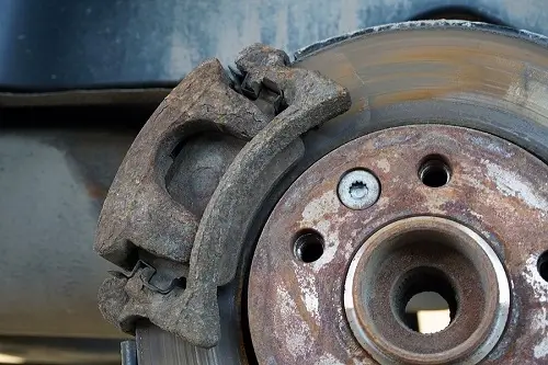 What Happens If You Don't Replace Your Brake Pads? | Repair One in Klein/Sprin, TX. Closeup image of worn-out brake pad, disc rotor, and caliper.