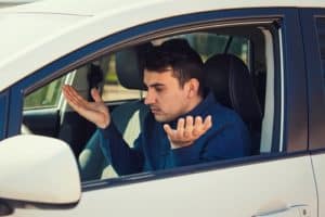 My Car is Acting Strange - Which Services Do I Need? | Repair One in Spring & Klein, TX. Image of perplexed young male driver shrugging shoulders and having problems with his car.