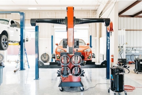 Professional Wheel Alignment Services | Repair One Auto | The Woodlands, TX. image of orange car on alignment machine in shop.