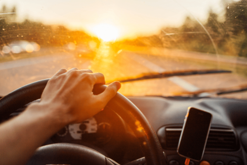 Repair One Tire & Auto – car maintenance car maintenance, auto repair in The Woodlands, TX at Repair One Tire & Auto. Driving toward the setting sun with visible glare through a dirty windshield, highlighting the need for clean glass and safe driving conditions.
