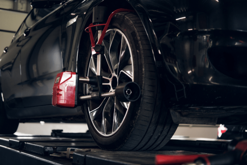 Repair One Tire & Auto – Wheel alignment wheel alignment, auto repair in The Woodlands, TX at Repair One Tire & Auto. Close-up of a car’s front wheel on an alignment rack with sensors and equipment attached during a wheel alignment service.